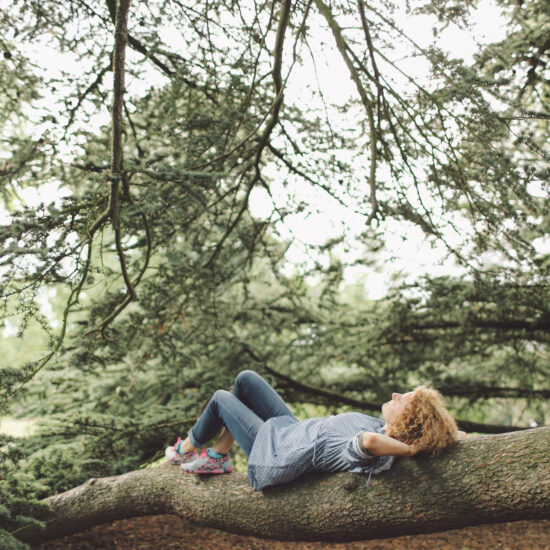 Woman resting peacefully on a tree branch in a forest