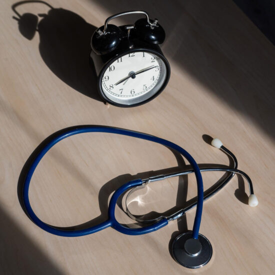 Clock and stethoscope on a wooden table representing long-term outcomes