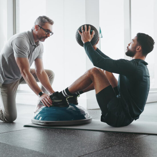 Therapist coaching an athletic patient through a Bosu ball exercise